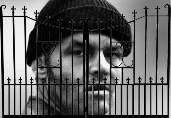 oversize criminal stereotype head looking through black gates